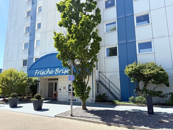 Un bâtiment moderne à la façade bleue et blanche, avec une enseigne indiquant « Frische Brise », et une petite entrée avec un escalier.