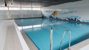 An indoor swimming pool with clear blue water, tiled walls, and a metal ladder. - Frische Brise, September 2—Newly Renovated Vacation Rental - Haus Frische Brise (Cuxhaven)