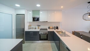 A modern kitchen with a built-in oven, microwave, and stainless steel refrigerator. - Apartamento El Nido - Mar de Pulpi (San Juan de los terreros)