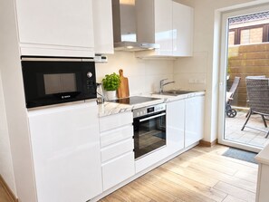 A modern kitchen with white cabinetry, a Bosch microwave, a built-in oven, and a sink. - DS2 - Nordic-style vacation rental near the beach for 4 people - House (Cuxhaven)