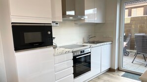A compact kitchen with white cabinetry, a Bosch microwave, a built-in oven, and a sink. - DS2 - Nordic-style vacation rental near the beach for up to 4 people - House (Cuxhaven)