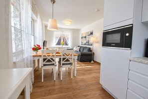 A modern kitchen with a Bosch microwave, a dining area with a wooden table and white chairs, and a grey sofa. - DS2 - Nordic-style vacation rental near the beach for 4 people - House (Cuxhaven)