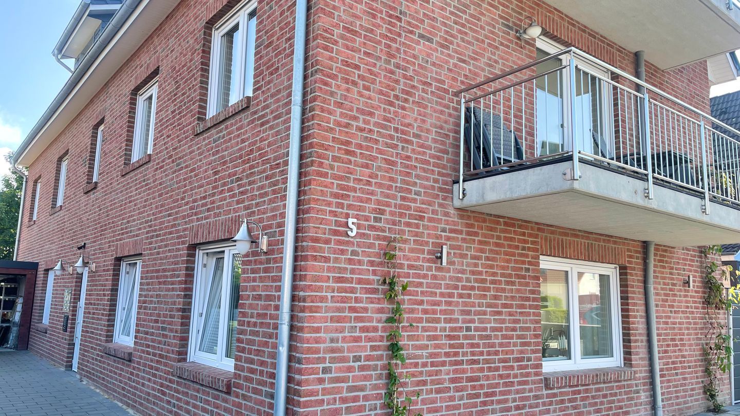 Ein rot backsteins Gebäude mit Balkon, Fenstern und der Hausnummer 5.