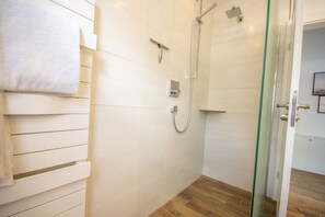 Une salle de bain avec une douche à parois de verre, un porte-serviettes et un plancher en bois.
