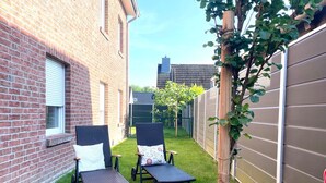 A backyard with two wicker chairs, a small tree, and a brick building. - DS2 - Nordic-style vacation rental near the beach for up to 4 people - House (Cuxhaven)