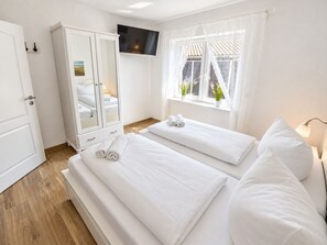 A hotel room with two beds, a wardrobe, a television, and a window with curtains. - DS2 - Nordic-style vacation rental near the beach for 4 people - House (Cuxhaven)