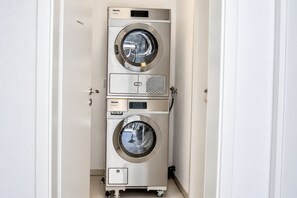 Een compacte, roestvrijstalen wasmachine met drie niveaus, geschikt voor professioneel gebruik, in een smalle gang.
