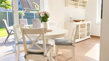 Ein Essbereich mit einem runden Tisch, weißen Stühlen und einer Blumenvase.