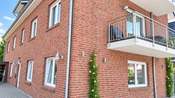 Un bâtiment en briques rouges, doté d’un balcon, de fenêtres blanches et d’un numéro « 5 » bien visible.