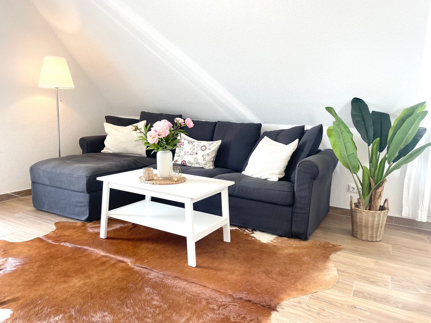 Ein Wohnzimmer mit Sofa, Couchtisch, Lampe, Pflanze und einem Teppich aus Rindsleder.