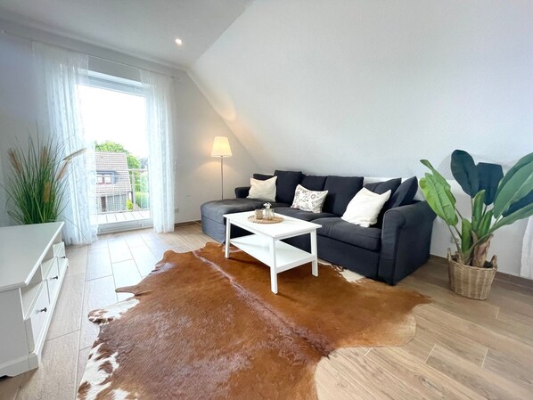 A modern living room with a sofa, a coffee table, a lamp, and a cowhide rug.