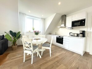 Et moderne køkken med hvide skabe, indbygget ovn og mikrobølgeovn.