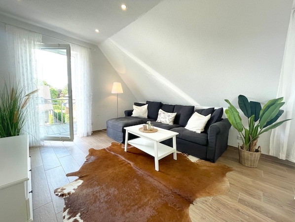 A modern living room with a sofa, a coffee table, a lamp, and a potted plant.