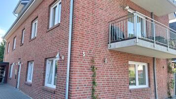 Ein rot backsteins Gebäude mit Balkon, Fenstern und der Hausnummer 5.