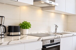 A modern kitchen with a stainless steel range hood, a built-in oven, and a sink with a faucet.