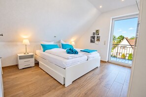 A bedroom with a bed, bedside tables, and a view of the outside.