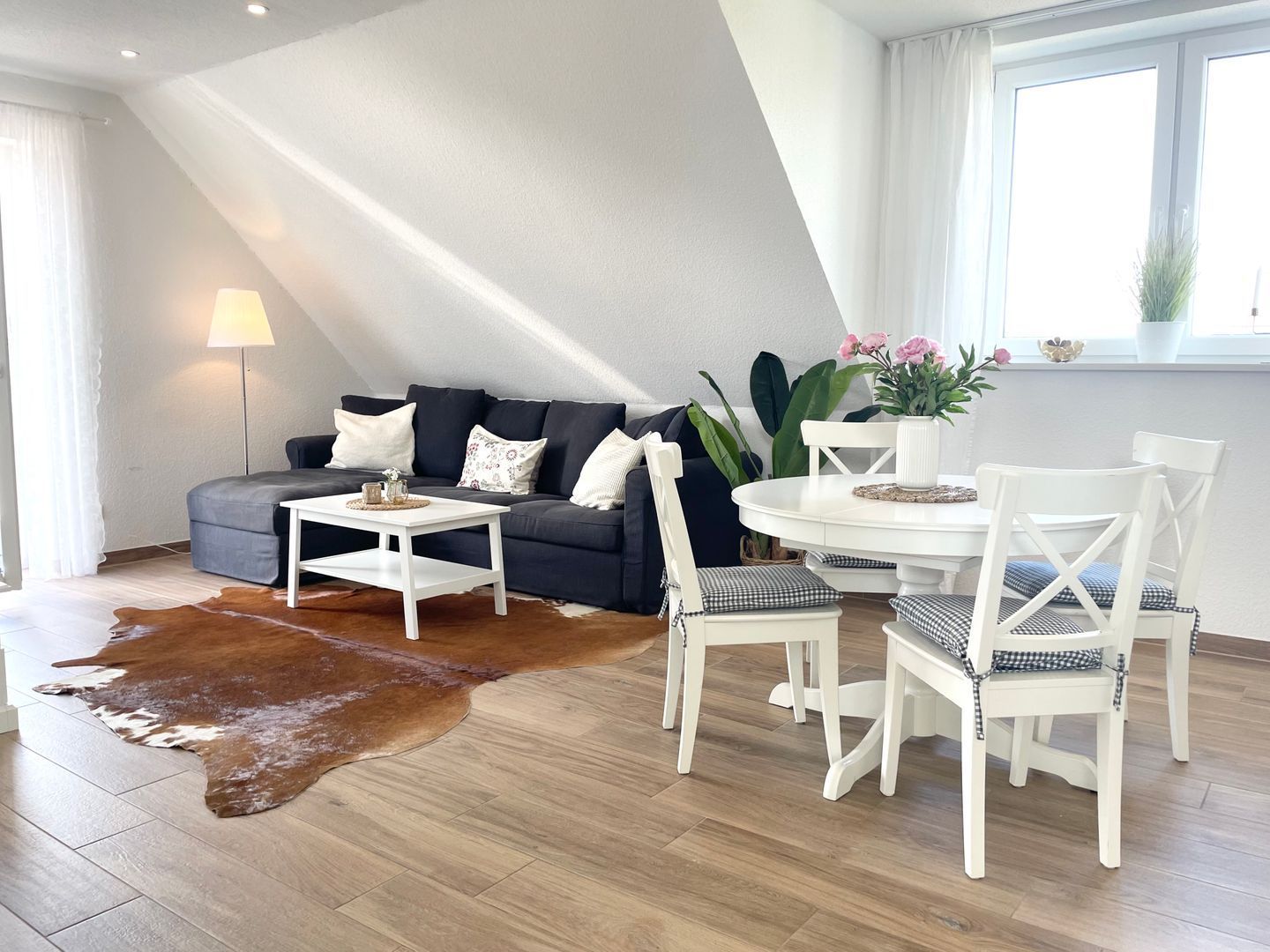 En moderne stue med sofa, sofabord og spisebord med stole.
