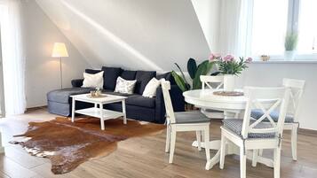 En moderne stue med sofa, sofabord og spisebord med stole.