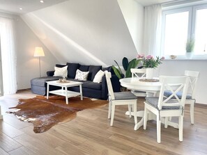 En moderne stue med sofa, sofabord og spisebord med stole.