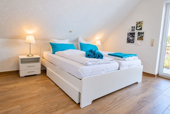 A modern bedroom with a bed, nightstands, and a window.