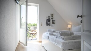 Ein Schlafzimmer mit Bett, Tür und Blick ins Freie.