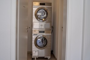 A compact, stainless steel, wall-mounted washer and dryer unit with a control panel and a small storage compartment. - DS5 - Strandnahe Modernes Ferienapartment für bis zu 4 Personen in Duhnen - Duhner Strand (Cuxhaven)