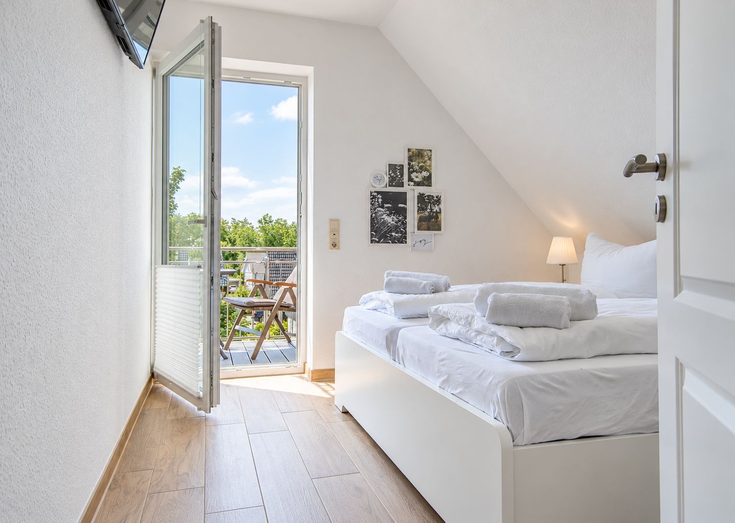 A bedroom with a bed, a door leading to a balcony, and a view of the outdoors.