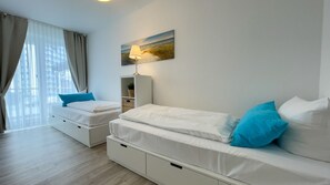 A bedroom with two beds, a nightstand, a lamp, and a painting on the wall.