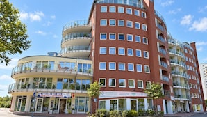A multi-story building with a curved facade, balconies, and ground-level commercial spaces.