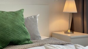 A neatly made bed with pillows, a bedside lamp, and a nightstand.