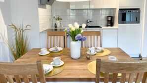 Una cocina moderna con armarios blancos, una campana extractora de acero inoxidable y un horno empotrado.