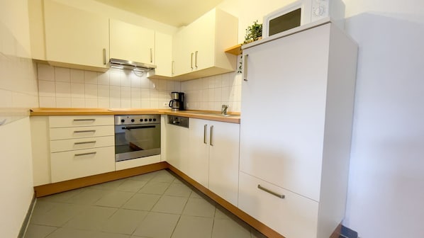 A kitchen with white cabinets, a built-in oven, a microwave, and a coffee maker.