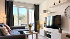 Una sala de estar moderna con un sofá, una mesa de centro, televisor y elementos decorativos.