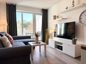 A modern living room with a sofa, coffee table, TV, and decorative items.
