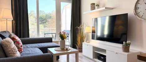 A modern living room with a sofa, coffee table, TV, and decorative items.