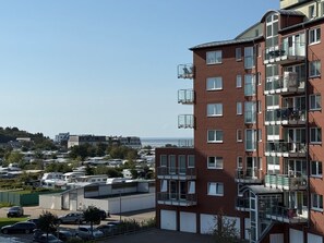 A multi-story residential building with balconies, a parking area, and a view of the sea. - A3.1 - Modern, cozy vacation apartment, close to the beach for up to 6 people - House (Cuxhaven)