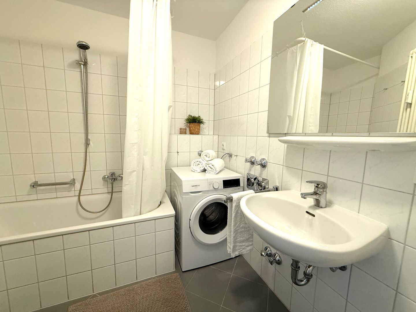 Un baño moderno con bañera, lavadora y lavamanos.
