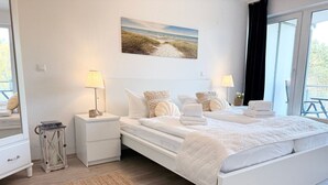 Een slaapkamer met een bed, nachtkastjes, lampen, een vloerkleed en een schilderij aan de muur.