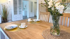 A dining area with a wooden table, white plates, a cup, and a vase with flowers.