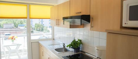 Una cocina moderna con armarios de madera, una estufa negra, un fregadero y un microondas.