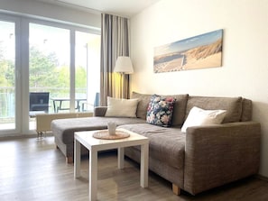 Ein Wohnzimmer mit einer Couch, einem kleinen Tisch, einer Lampe und einem Bild an der Wand.