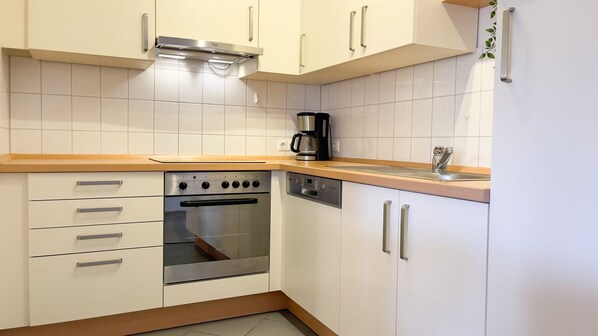 A kitchen with white cabinets, a stainless steel oven, a coffee maker, and a dishwasher.