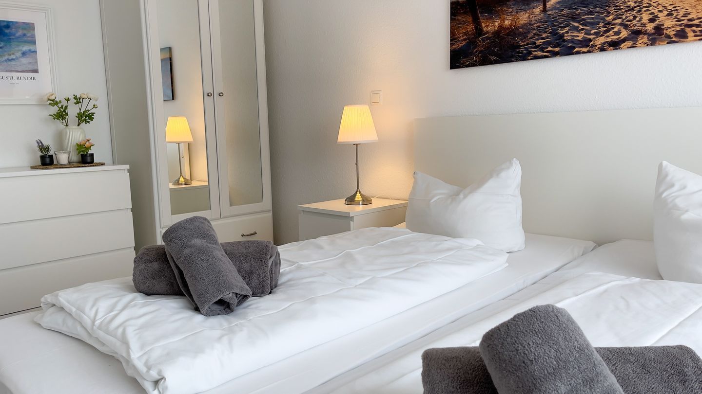 Et hotelværelse med en seng, to sengeborde, et natbord, et spejl og et billede på væggen.