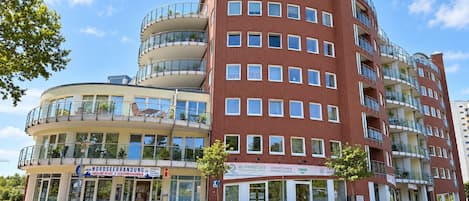 Un edificio de varios pisos con fachada curva, balcones y locales comerciales en la planta baja.