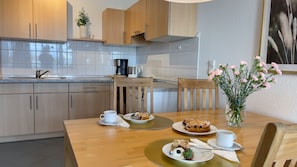 A modern kitchen with wooden cabinets, a coffee maker, and a dining table set with plates of food and cups. - B1.4 - Dream vacation apartment with 2 balconies for 1-7 persons only 200m from the beach - (Cuxhaven)