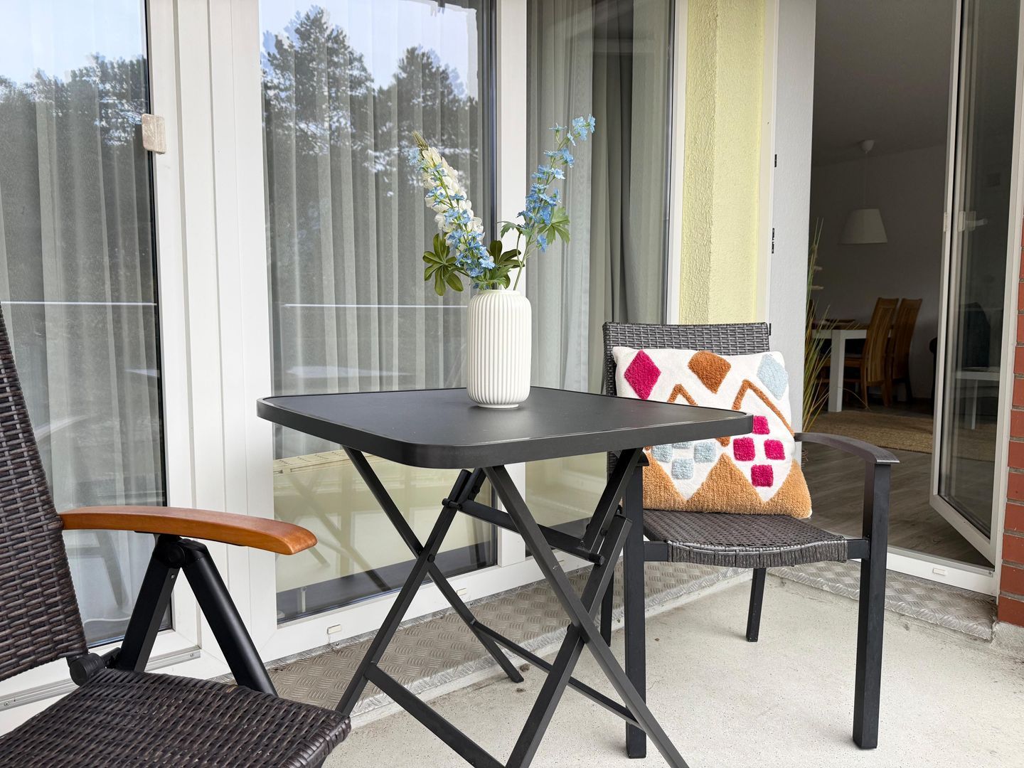 Ein Balkon mit Tisch, zwei Stühlen und einem Blumentopf.