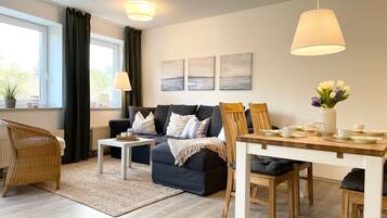 Ein modernes Wohnzimmer mit einer Couch, Esstisch, Stühlen und Kunstwerken an der Wand.