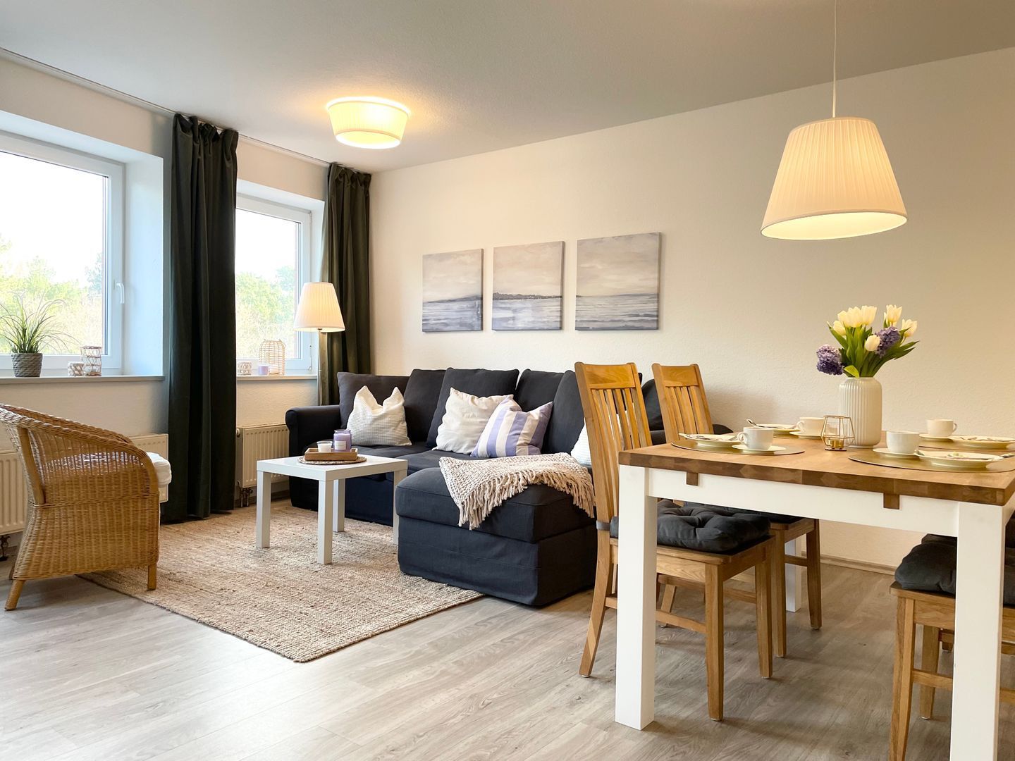 Een moderne woonkamer met een bank, eettafel, stoelen en kunst aan de muur.