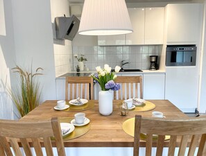 Une cuisine moderne avec des armoires blanches, une hotte de cuisinière en acier inoxydable et un four encastré.