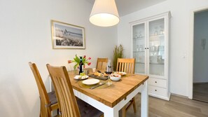 A dining area with a wooden table, chairs, a glass cabinet, and a framed picture on the wall.